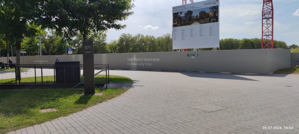 Ein grau bemalter Bauzaun aus Holz. Auf diesem stehen die Worte: "Der Fency Bauzaun. Fortsetzung folgt..."